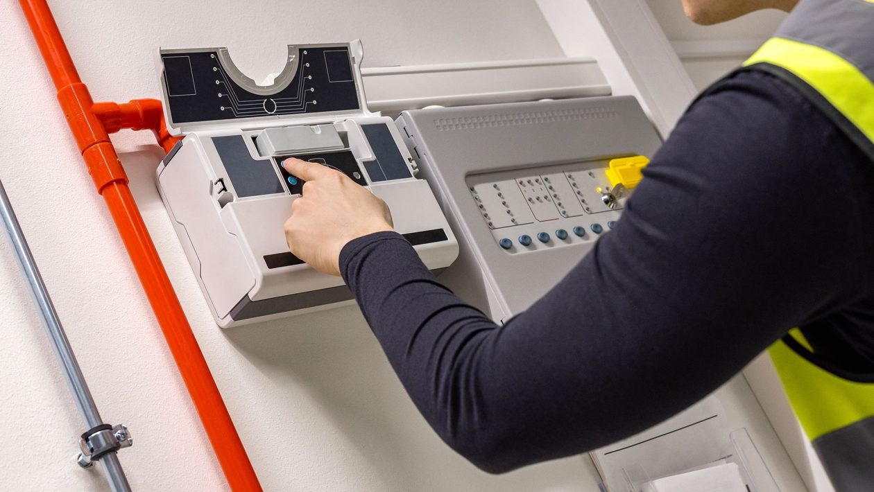 Male Ttechnician checking smoke detector in dealership