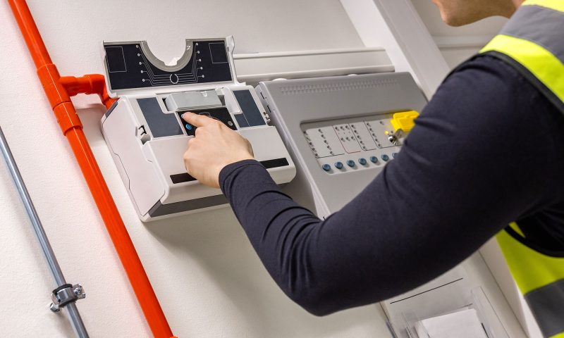 Male Ttechnician checking smoke detector in dealership